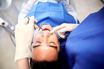 people, medicine, stomatology and health care concept - close up of female dentist with dental mirror checking up male patient teeth at dental clinic ...-stock-photo